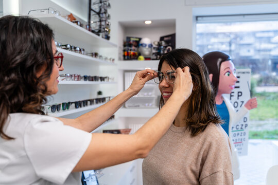Optician Fitting Glasses On Customer