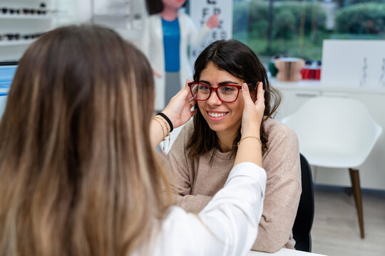 Optician Fitting Eyeglasses At Table