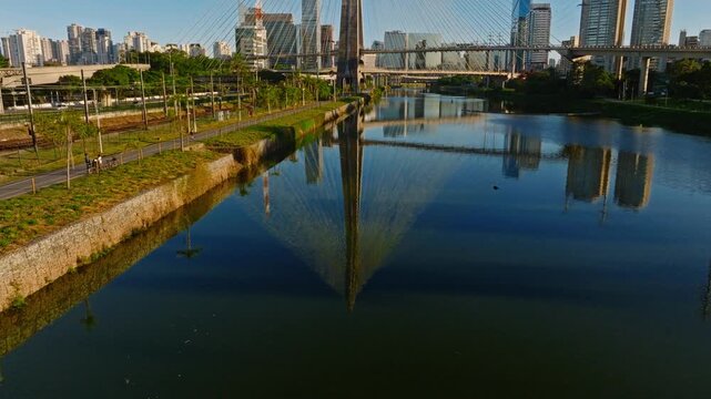 Aerial reveal of Octavio Frias de Oliveira bridge starting from water reflection to skyward tilt, Sao Paulo, Brazil - DJI Mavic 3