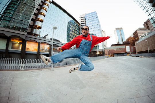 Man in red shirt jumping with excitement in city