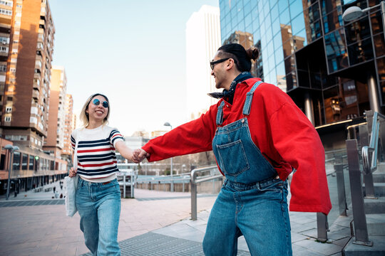 Happy couple holding hands walking in city street