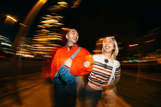 Young couple enjoying city nightlife long exposure motion blur