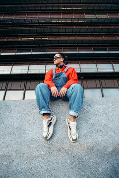 Young man sitting in overalls looking away