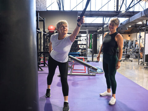 Woman Using Resistance Bands in Gym with guidance from Trainer