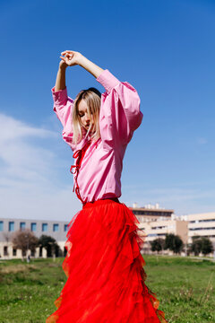 Blonde woman posing in field with red skirt