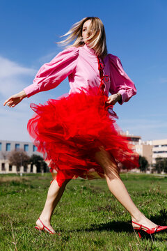 Woman twirling in red tulle skirt outdoors