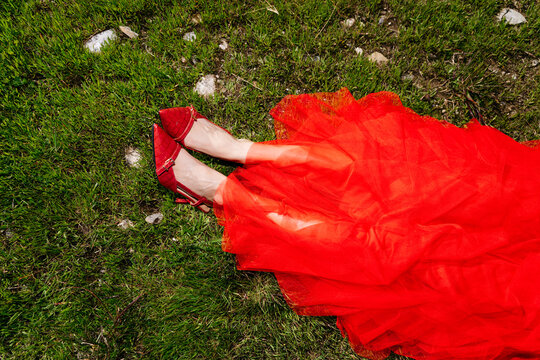 Woman's legs with red dress and shoes on grass