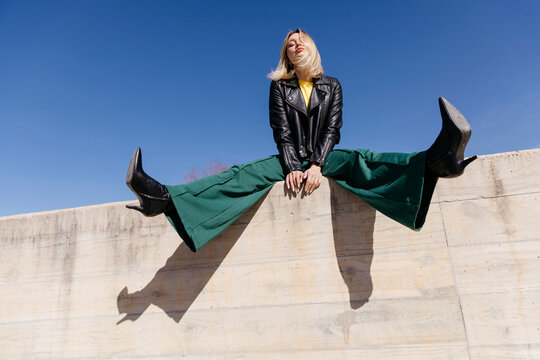 Woman sitting on concrete wall spreading legs
