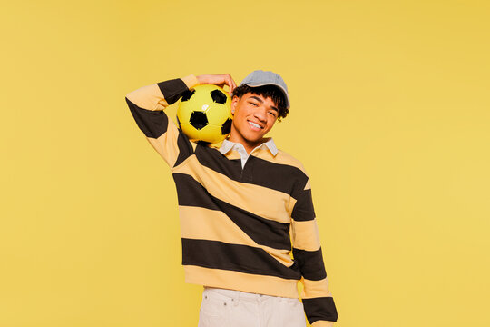 Enthusiastic man smiling holding soccer ball on shoulder