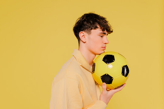Man holding a soccer ball on yellow background