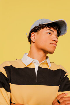 Cool man wearing denim cap and striped polo shirt against yellow wall