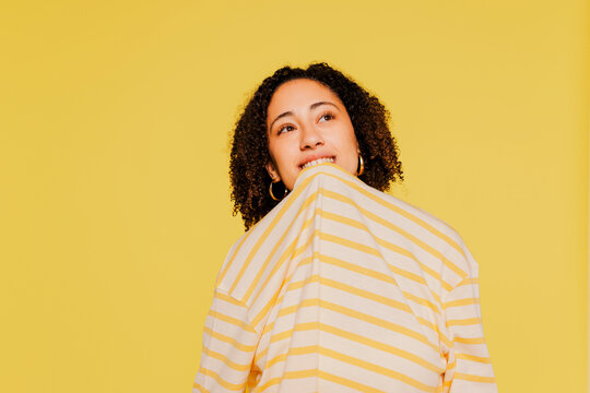Woman biting shirt against yellow background
