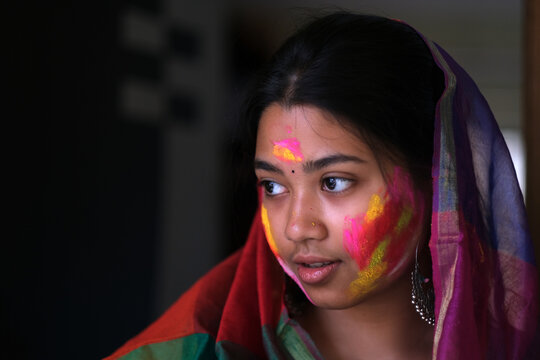 Young Indian lady face smudged with colourful powders in holi festival