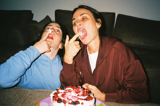 Mother and daughter tasting cake frosting