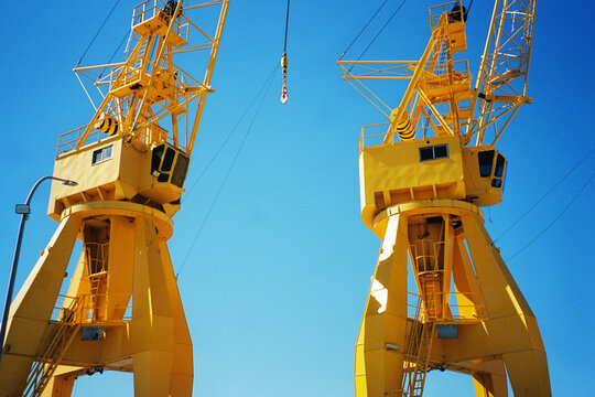 Two yellow harbor cranes against blue sky 