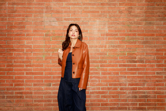 Woman Poses in Front of a Brick Wall Wearing a Leather Jacket