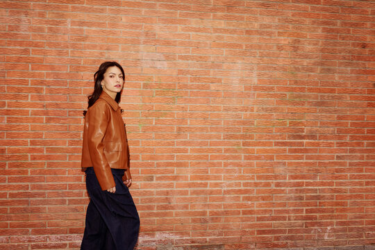 Woman Walks Near Brick Wall Wearing Brown Leather Jacket