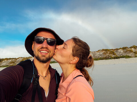 Woman Kissing Man on Beach with Rainbow