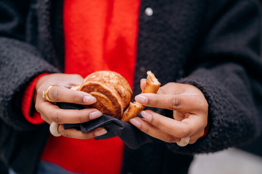 A woman eats a bun in the city