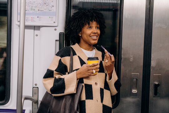 A woman recording a voice message in a subway car