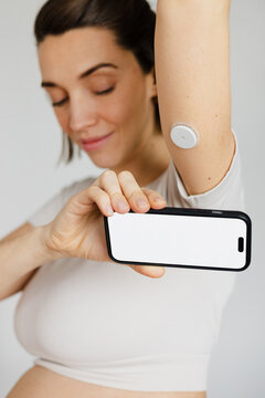 Pregnant woman continuously monitoring glucose with smartphone app