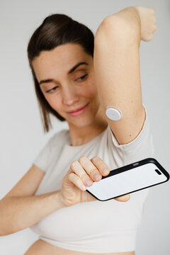 Woman measuring glucose levels with continuous sensor and smartphone