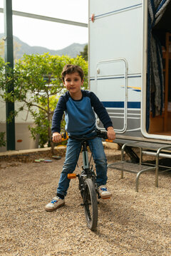 Young boy riding bicycle on gravel at campsite