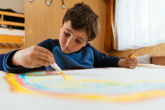 Kid drawing rainbow with colorful markers on paper