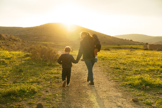 Mother and children walking on path at sunset