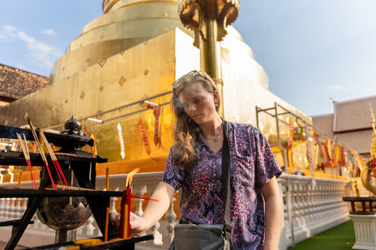 Visitor at Golden Temple in Thailand Lights Incense During Prayer