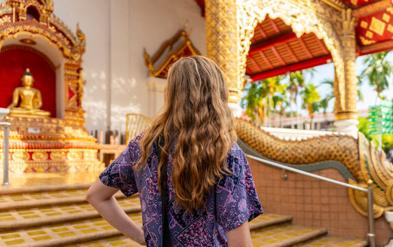 Woman Stands in Front of a Temple With a Statue in the Background