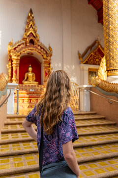Visitor Admires Golden Buddha in a Temple in Thailand