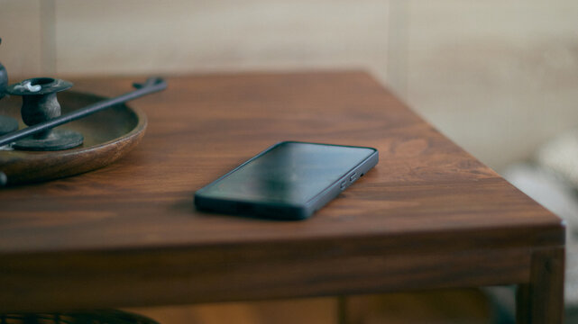 A black mobile phone on a coffee table
