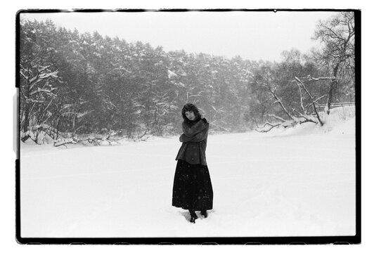 Film B&W Portrait of a Woman Raising Arm in Snowy Field