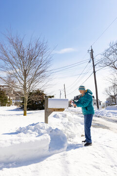 Senior woman gets mail from Mailbox winter