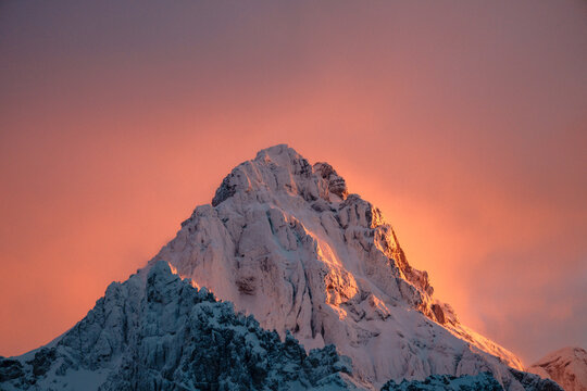 Aerial view of the snow-covered peak of Mount Triglav in Triglav National Park during a vibrant sunset with a pink sky Bohinjsko jezero, Slovenia.