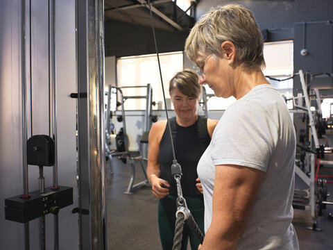 Personal trainer coaching client on gym equipment