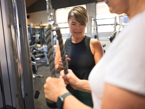Fitness Instructor Helps Client With Workout at Gym