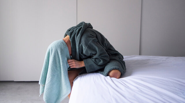 Woman Drying Hair on Bed in Bathrobe