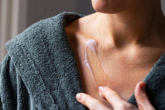 Woman Applying Moisturizer to Chest and Collarbone