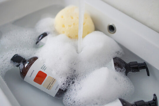 Shampoo Bottles With Bubbles in Bathtub and Sponge