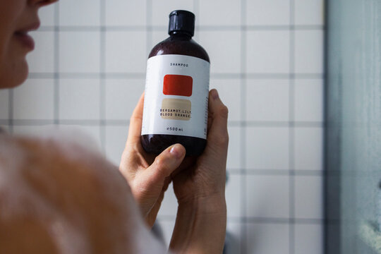 Woman Holding Shampoo Bottle in Shower Bathroom