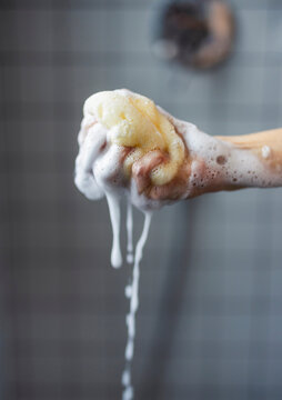 Hand Holding Soapy Sponge In Shower