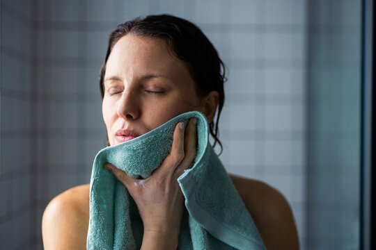 Woman Drying Her Face With Towel In Bathroom