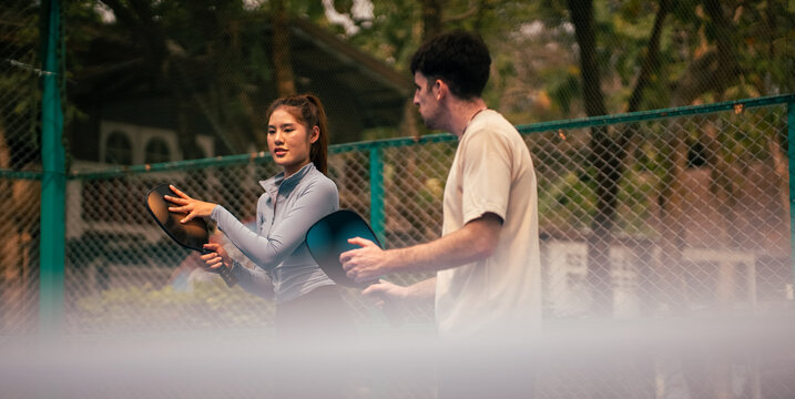 Couple playing pickleball on court, learning and improving