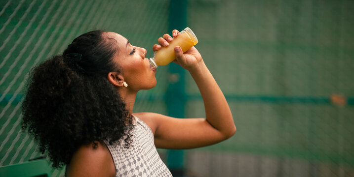 Black woman refreshing with healthy juice outdoors after excercising