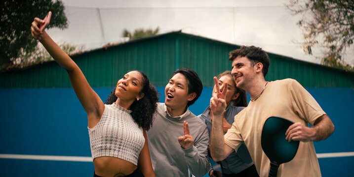 Diverse friends enjoying pickleball, taking a selfie on court