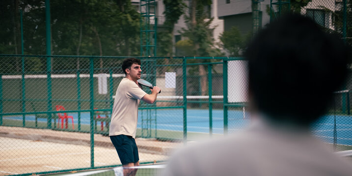 Pickleball player concentrating on game, swinging paddle to hit ball