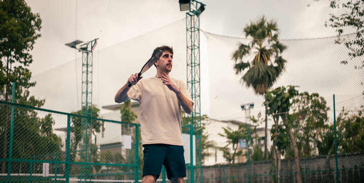 Super focused man playing pickleball game on outdoor court in Bangkok