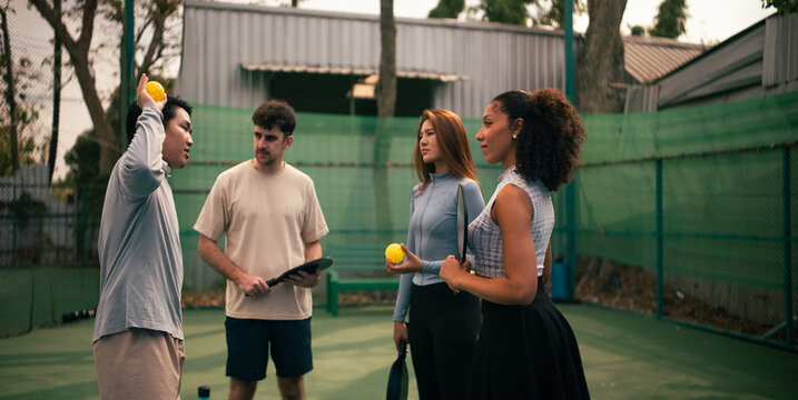 Group of diverse friends engaging in pickleball game on court in BKK